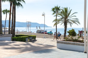 A beachside promenade with palm trees, benches, and a lifeguard tower. - Las Flores de Burriana 5 by Casasol (Nerja)