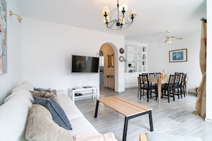 A modern living room with a sofa, TV, and dining area. - Las Flores de Burriana 5 by Casasol (Nerja)