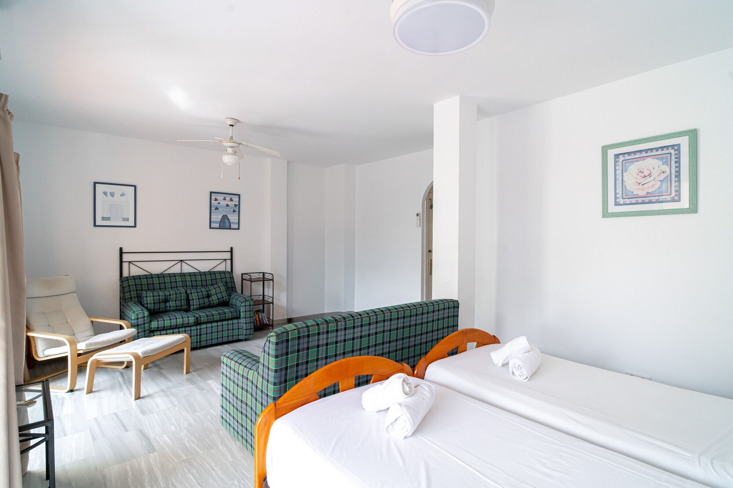 A hotel room with a bed, a sofa, a chair, and a small table.
