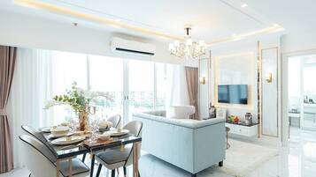 A modern living room with a dining area, a sofa, a TV, and a chandelier.