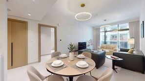 A modern living room with a dining area, a sofa set, and a television. - Airy 1 Bedroom in JVC l Pool & Gym access l near Circle Mall (JVC)