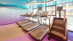 Ett gym med löpband, en trappmaskin och en digital display.