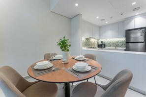 A modern dining area with a round table, chairs, and a vase with a plant. - Airy 1 Bedroom in JVC l Pool & Gym access l near Circle Mall (JVC)