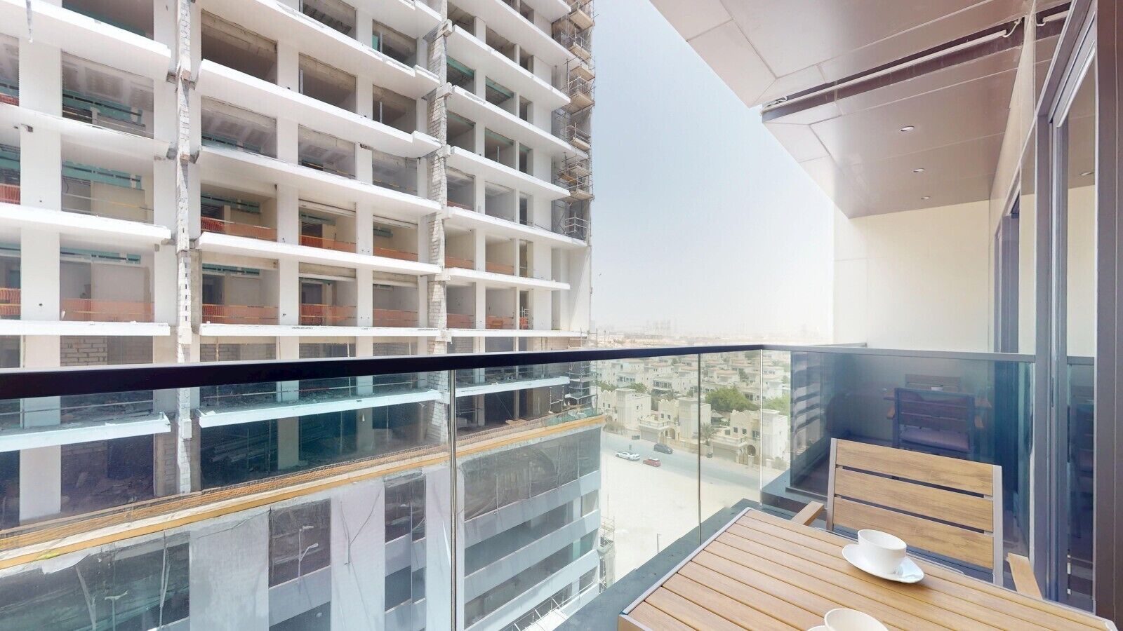 Un bâtiment moderne doté d’un balcon en verre offrant une vue panoramique sur la ville.
