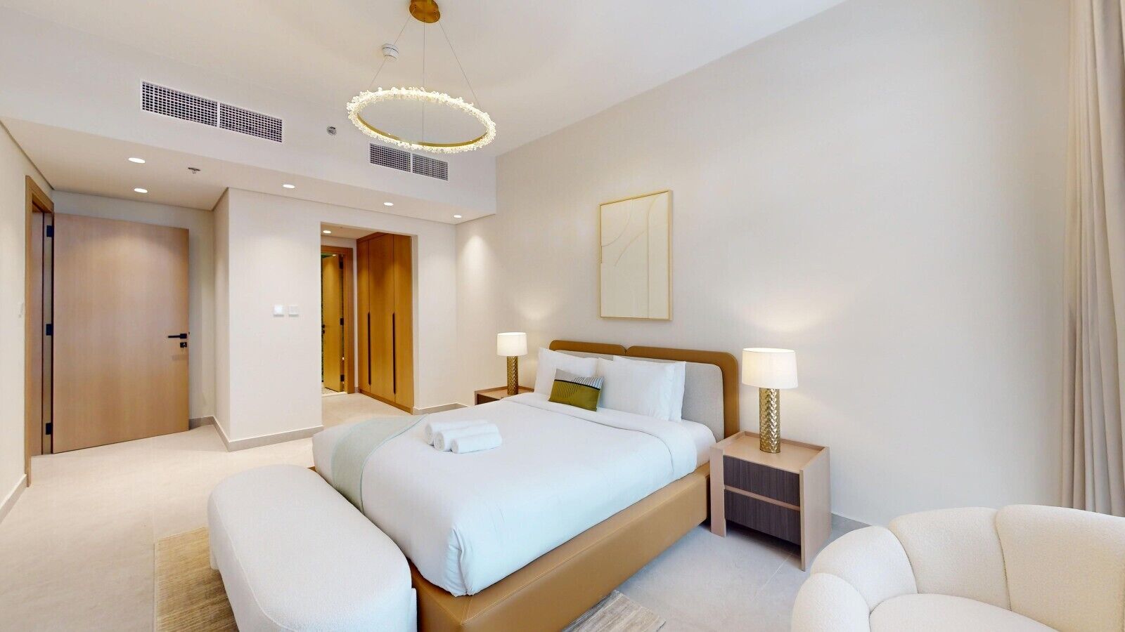 Een hotelkamer met een groot bed, nachtkastjes, een stoel en een plafondlamp.