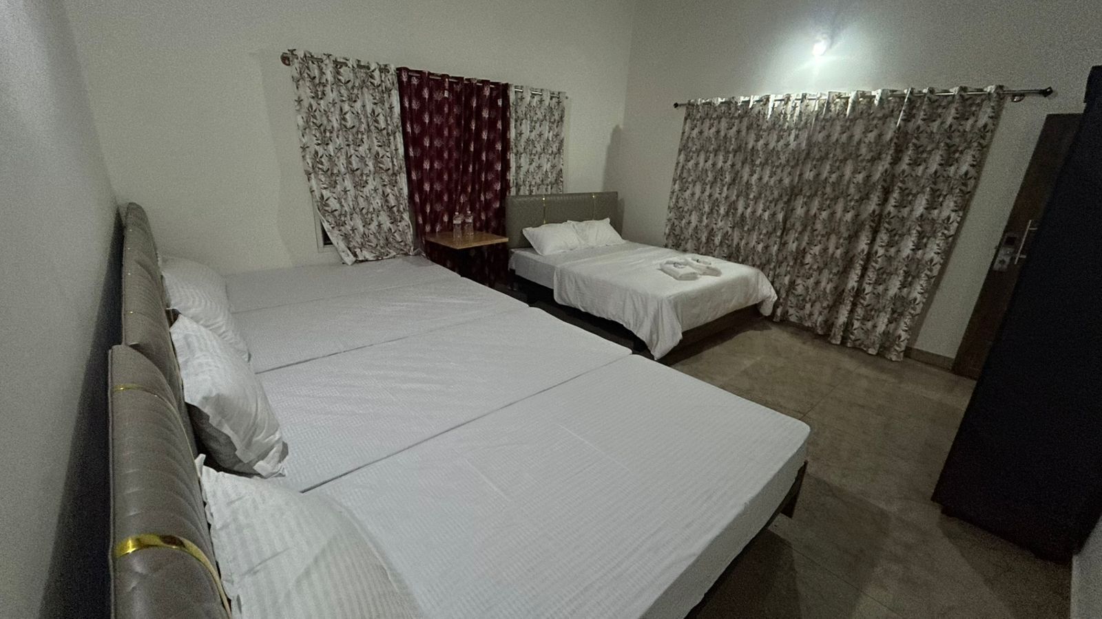 A hotel room with two beds, a wooden headboard, a nightstand, and a wardrobe.