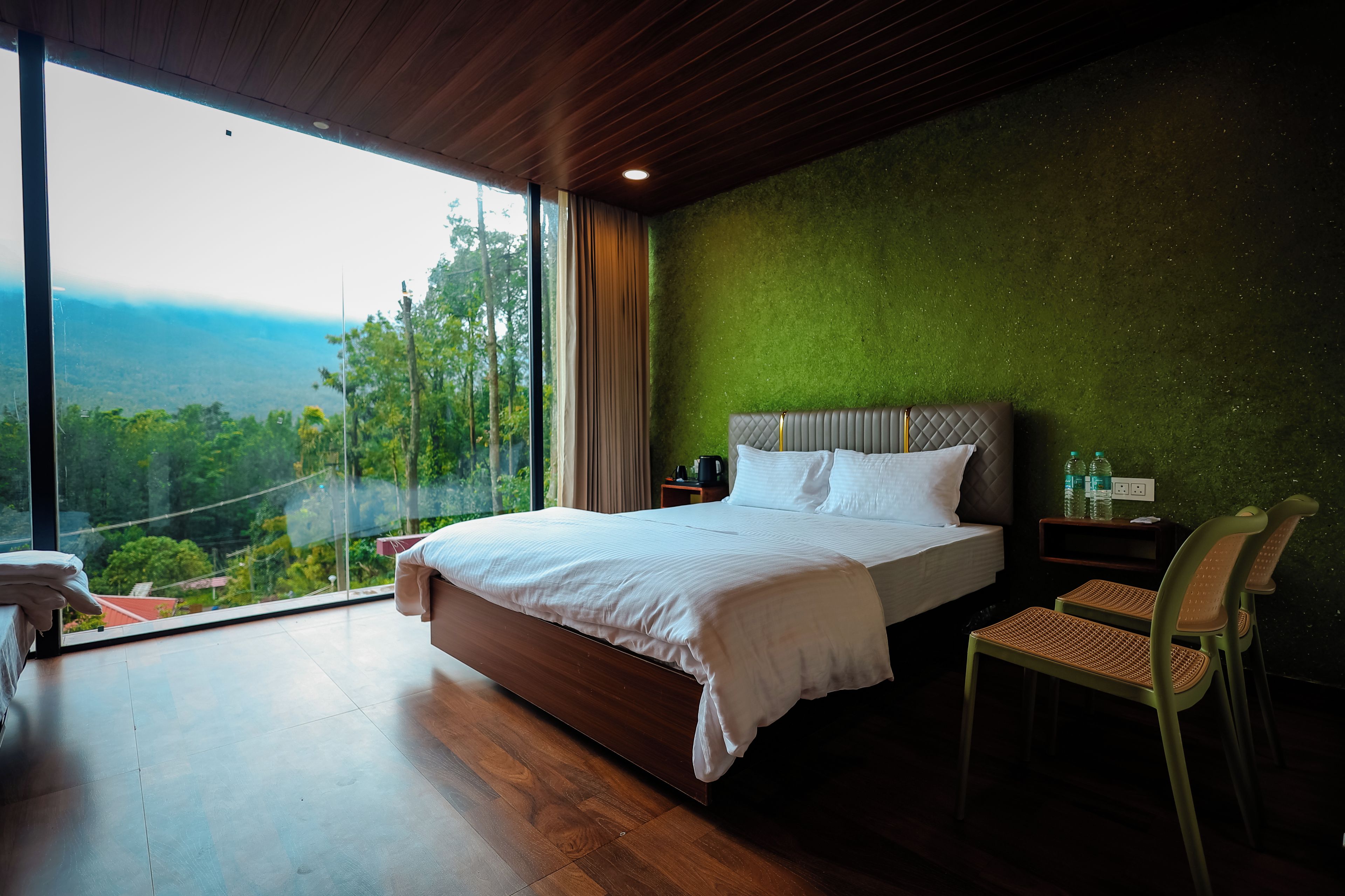 A bedroom with a large bed, a view of the outdoors, and a green wall.