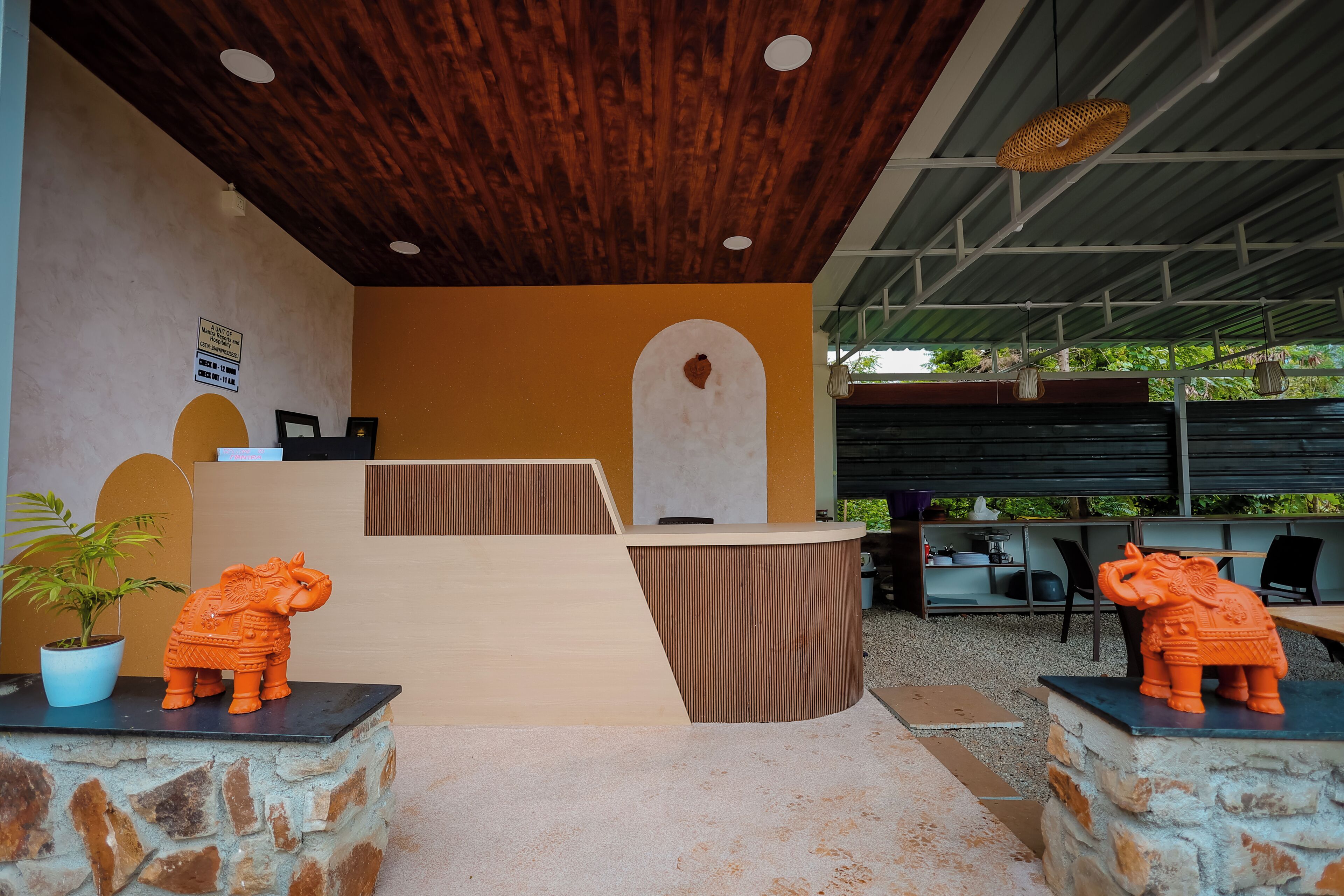 A reception area with a wooden ceiling, a reception desk, and two elephant statues.