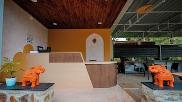 A reception area with a wooden ceiling, a reception desk, and two elephant statues.