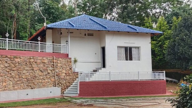 A two-story building with a stone wall and a red base. - Honey Drop by Mantra (Chikkamagaluru)