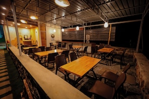 Un comedor interior con varias mesas y sillas, una barra y una estructura de techo de madera.
