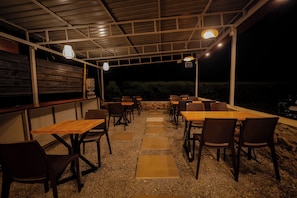 Un patio al aire libre con mesas y sillas, un dispensador de agua y vistas al cielo nocturno.