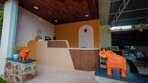 A reception area with a wooden ceiling, a reception desk, and two decorative animal figures on pedestals. - Honey Drop by Mantra (Chikkamagaluru)