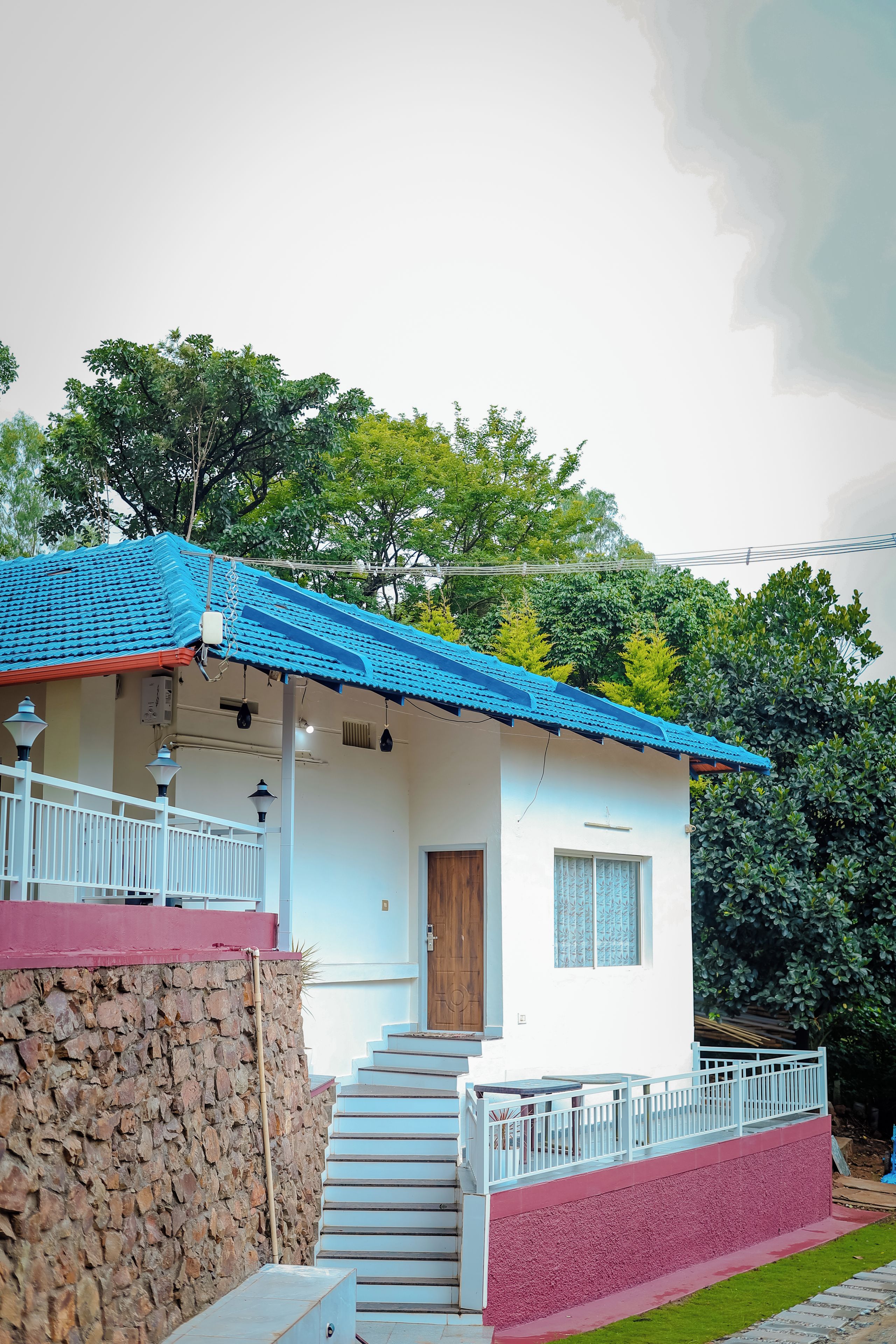 A single-story house with a blue tiled roof, a wooden door, and a small window with decorative shutters.