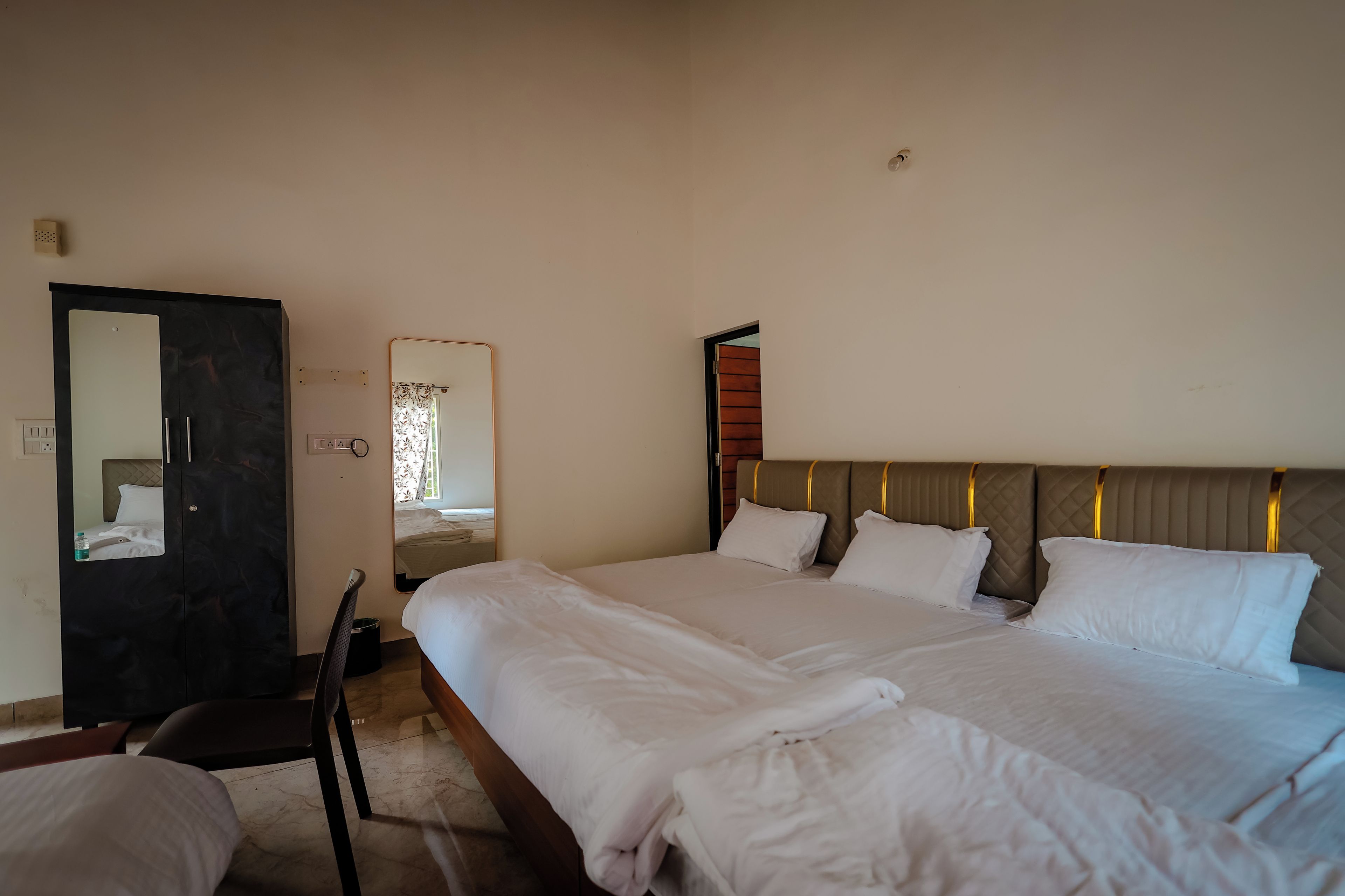 Una habitación de hotel con una cama grande, un armario, un espejo y una puerta.