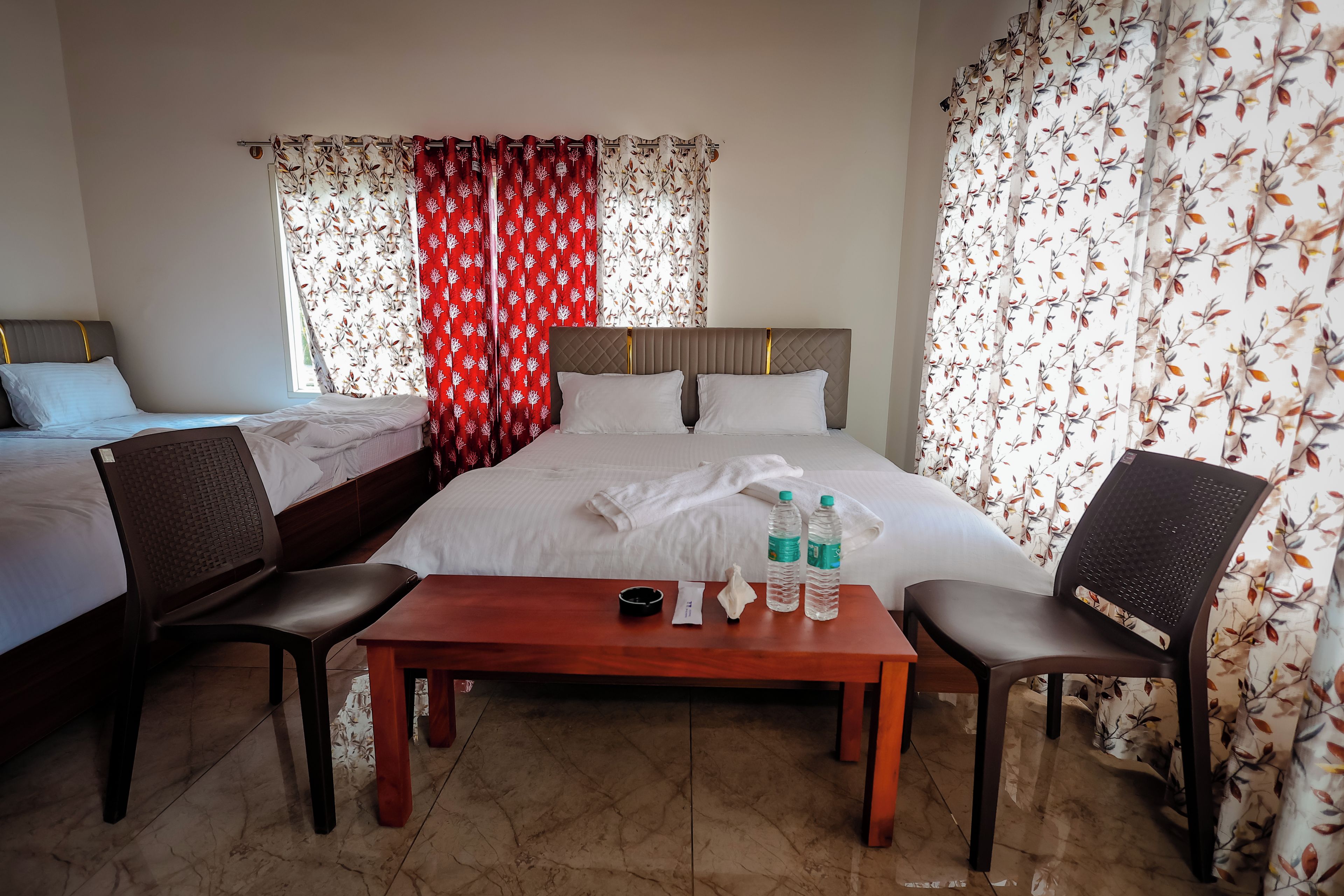 A hotel room with two beds, a wooden table, and a chair.