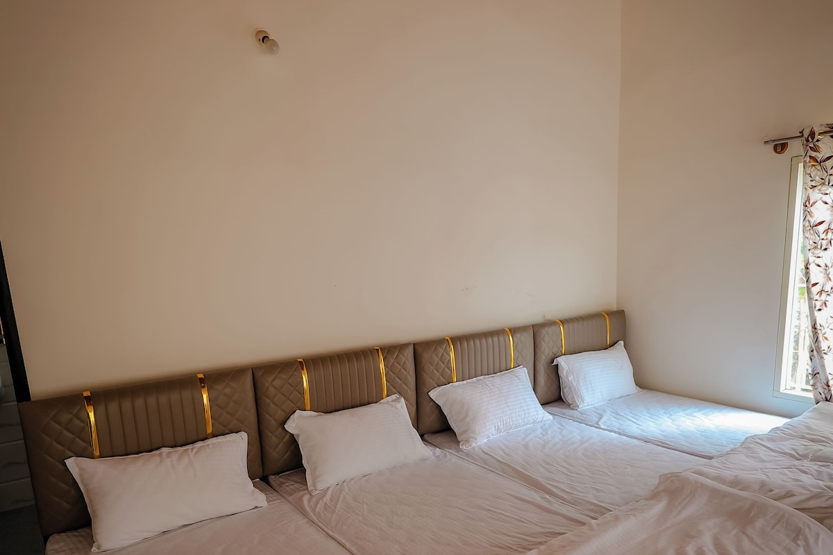 A room with a large bed, a wooden headboard, and a ceiling with exposed beams.