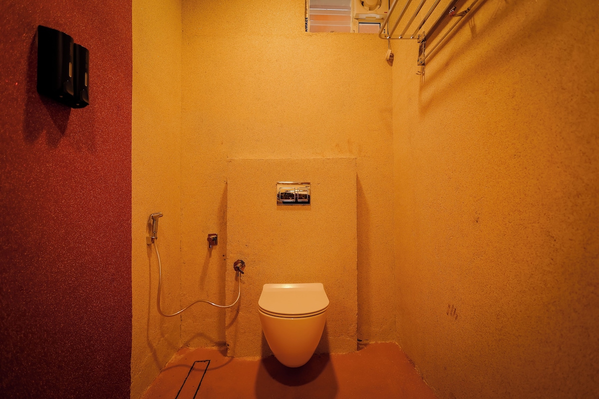 A small, compact bathroom with a toilet, a shower, and a towel rack.