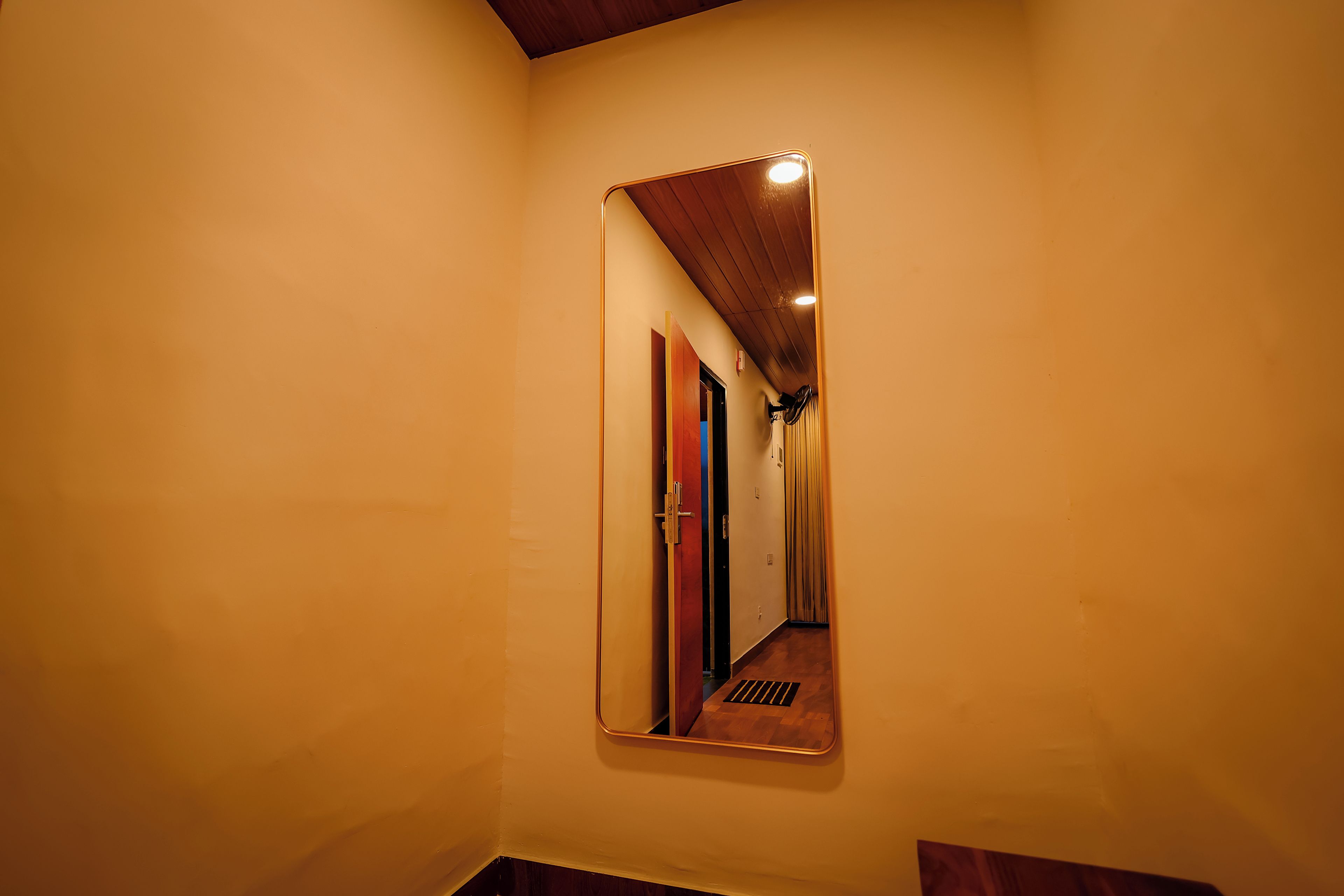 Un espejo refleja un pasillo con techo de madera y una puerta.