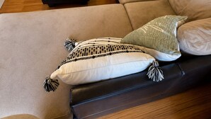 Een woonkamer met een bank, een voetenbankje en een decoratief vloerkleed.