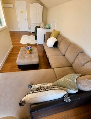 Ein Wohnzimmer mit einer Couch, einem Hocker und einem dekorativen Teppich.