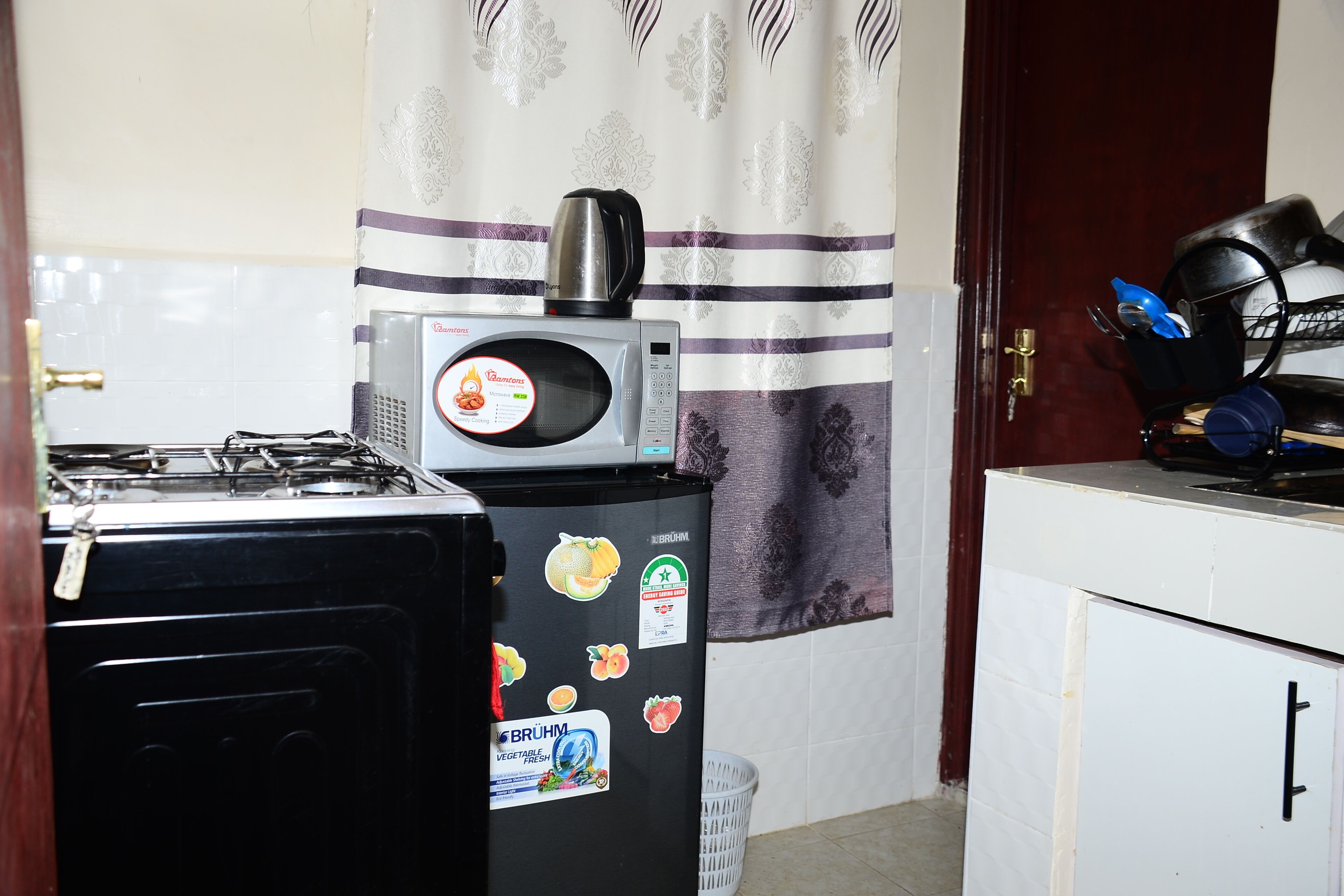 Una cocina compacta con estufa a gas, un refrigerador con calcomanías, microondas y cafetera.