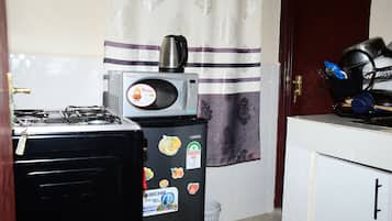 Una cocina compacta con estufa a gas, un refrigerador con calcomanías, microondas y cafetera.