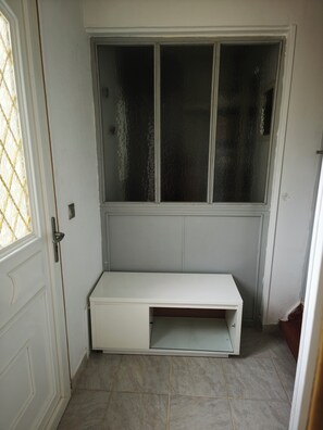 A room with a white bench, a window with frosted glass, and a door with a glass panel.