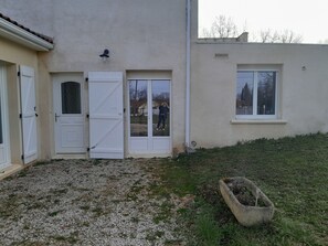A building with a gravel driveway, a concrete planter, and a white door with a window.