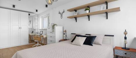 Une chambre avec un grand lit, un bureau et des étagères décorées de plantes.