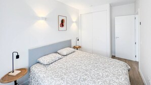 A bedroom with a bed, bedside tables, a wall-mounted light, and a door. - Modern Home in Vicálvaro (Madrid)