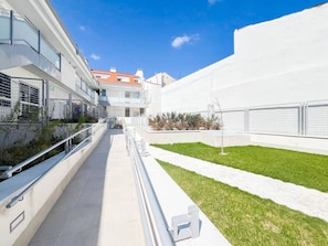 Un bâtiment moderne avec un chemin rectiligne menant à une entrée fermée par un portail.