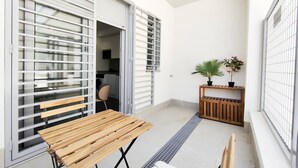 An outdoor patio with a wooden table, a bench, a potted plant, and a wooden bench with a slatted seat. - Modern Home in Vicálvaro (Madrid)