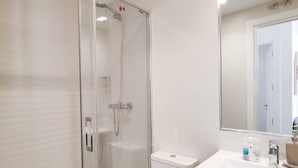 A modern bathroom with a glass-enclosed shower, a white sink, and a mirror above it. - Modern Home in Vicálvaro (Madrid)