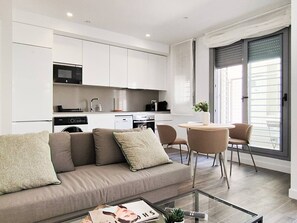 A modern living room with a sofa, a coffee table, and a dining area with chairs. - Modern Home in Vicálvaro (Madrid)
