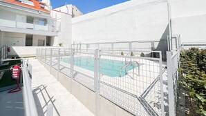 A swimming pool enclosed by a white fence, with a fire extinguisher and a small plant nearby. - Modern Home in Vicálvaro (Madrid)