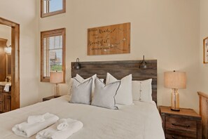 A neatly made bed with pillows, a bedside table with a lamp, and a wall with a motivational quote. - Peak a View  - Lux Cabin w Tri-State VIEWS at 4,200 Feet! (Beech Mountain)