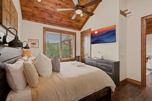 A bedroom with a bed, pillows, a dresser, a ceiling fan, and a wall-mounted TV. - Peak a View  - Lux Cabin w Tri-State VIEWS at 4,200 Feet! (Beech Mountain)