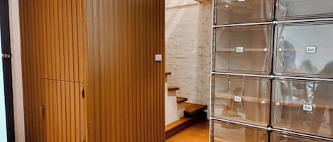 A room with a wooden wardrobe, a set of clear storage boxes, and a staircase.