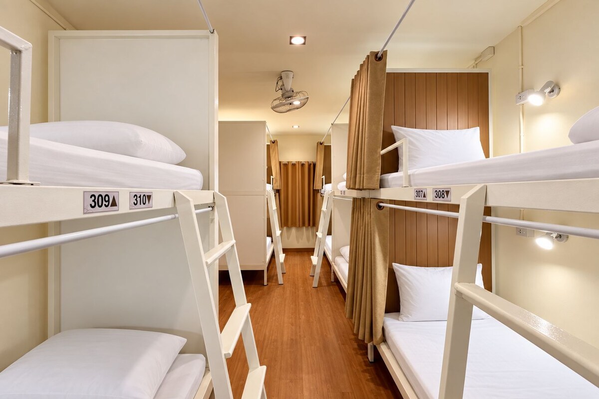Ett hotellrum med våningssängar, rum nummer 309 och 310, trägolv och en takfläkt.