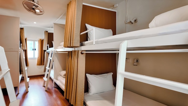Habitación con literas, una escalera, ventilador de techo y ventana.
