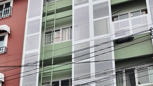 Un edificio de varios pisos con fachada verde y marcos de ventanas blancos.