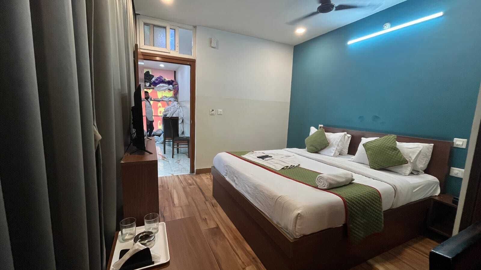 Hotellihuone, jossa on sänky, yöpöytä ja näkymä käytävälle.