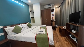 Habitación de hotel con cama, televisión, armario y escritorio.