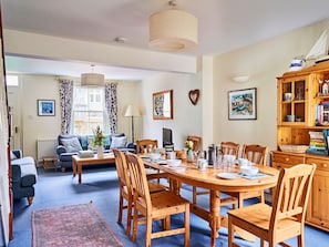 A dining area with a wooden table, chairs, and a bookshelf. - Finest Retreats | Garston (Salcombe)