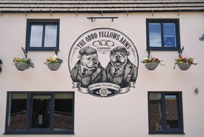 Un edificio con un emblema circular que muestra dos perros y el texto 'The Odd Fellows Arms Yorkshire Family & Friendship'.