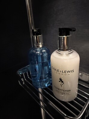 Dos botellas de productos de higiene personal sobre una estantería de metal.