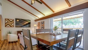 A dining area with a wooden table and chairs, a ceiling fan, and artwork on the walls. - The Airman House Pool-hot Tub-fun by Lackland AFB (San Antonio)