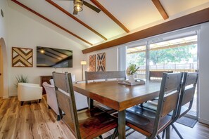 Ein Essbereich mit einem Holztisch und Stühlen, einem Deckenventilator und Kunstwerken an den Wänden.
