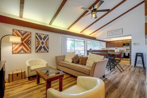 Ein modernes Wohnzimmer mit Sofa, Sesseln, Couchtisch und Deckenventilator.
